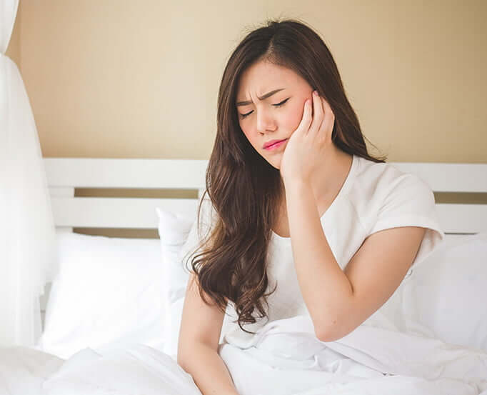 woman holding her jaw in pain