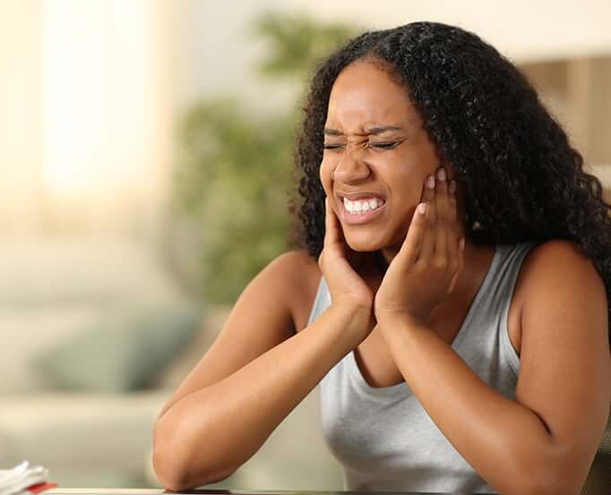 woman holding her jaw in pain