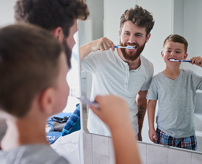 father and son brushing their teeth together