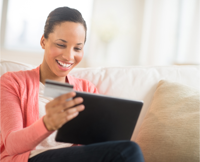 smiling woman sitting in front of a laptop with credit card